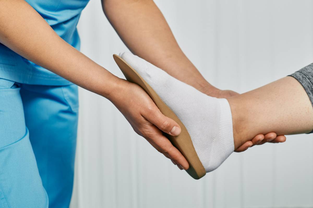 Medical professional helping a patient adjust shoe insoles to prevent foot wounds.